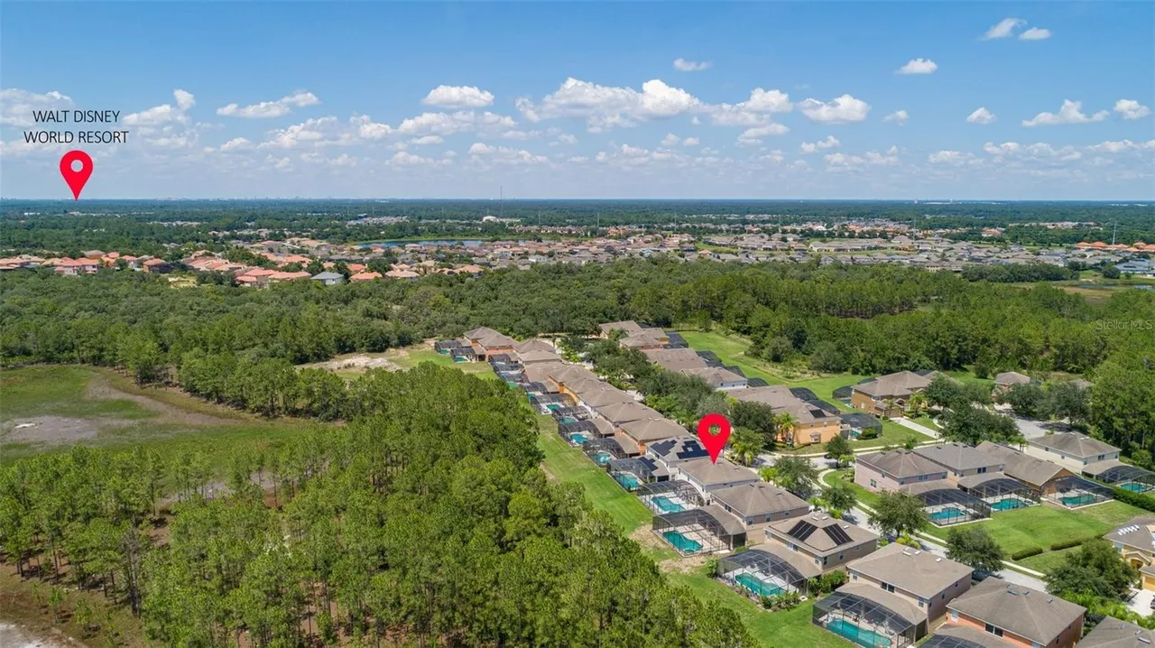 Aerial view of Watersong Resort: a row of villas with screened pools backing onto conservation woodland, with Davenport's rooftops stretching to the horizon